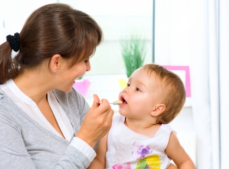 Mother Feeding Her Baby Girl with a Spoon の写真素材