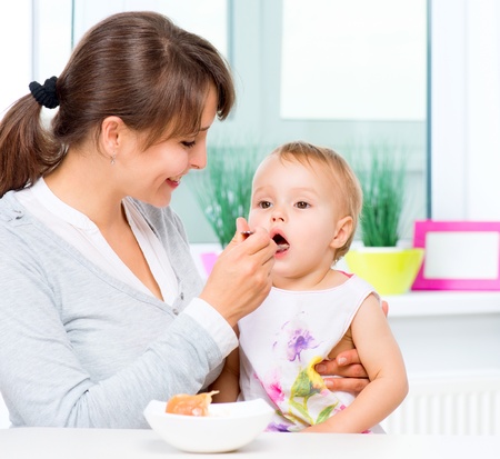 Mother Feeding Her Baby Girl with a Spoon の写真素材