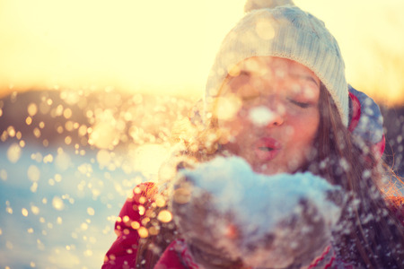 Beauty winter girl blowing snow in frosty park. Sunny day