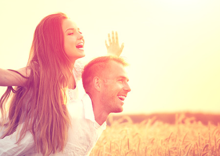 Happy couple having fun outdoors on wheat field over sunsetの写真素材