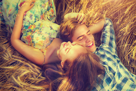 Happy couple relaxing outdoors on wheat field, love concept Happy couple relaxing outdoors on wheat field, love concept