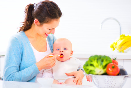 Mother feeding her baby girl with a spoon. Baby foodの写真素材