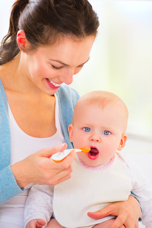 Mother feeding her baby girl with a spoon. Baby foodの写真素材