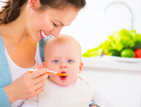 Mother feeding her baby girl with a spoon. Baby foodの写真素材