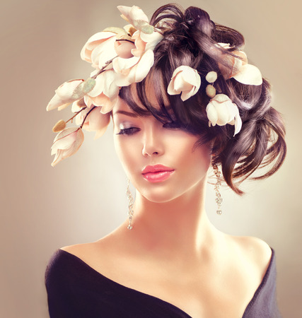 Beauty woman portrait. Fashion brunette girl with magnolia flowers hairstyleの写真素材