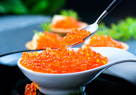 Caviar. Red caviar in spoon on a black background. Gourmet food closeupの写真素材