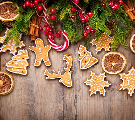 Christmas holiday border with gingerbread cookies, candy cane over wooden backgroundの写真素材