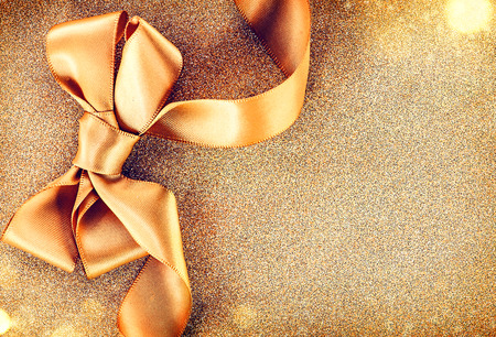 Christmas golden satin ribbon bow on a blinking holiday backgroundの写真素材