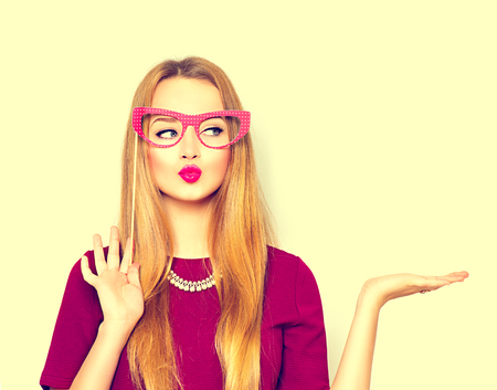Beauty girl with paper glasses on stick showing empty copy space on the open handの写真素材