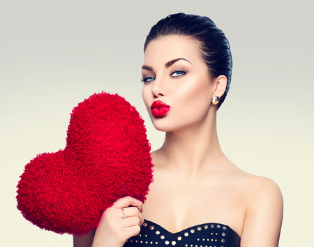 Gorgeous young brunette woman with heart shaped red pillowの写真素材