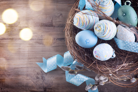 Easter concept. Colorful blue eggs in the nest over wooden backgroundの写真素材