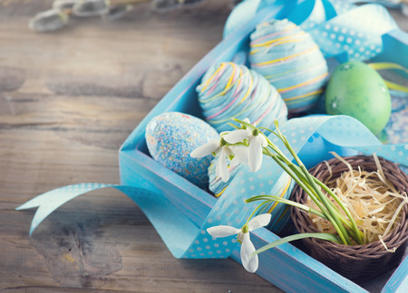 Easter concept. Colorful blue eggs and spring snowdrop flowers over wooden backgroundの写真素材
