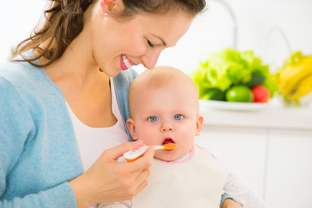 Mother feeding her baby girl with a spoonの写真素材