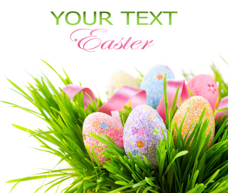 Easter colorful eggs on green spring grass isolated on white backgroundの写真素材