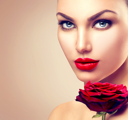 Beauty fashion model woman face. Portrait with red rose flowerの写真素材