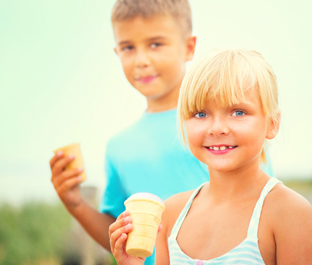 Two happy kids eating ice cream outdoorsの写真素材