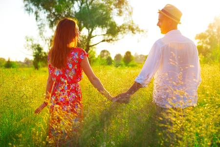 Couple holding hands and walking together on summer meadow fieldの写真素材