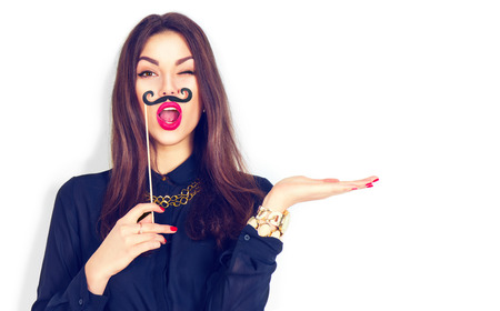 Winking model girl holding funny mustache on stickの写真素材