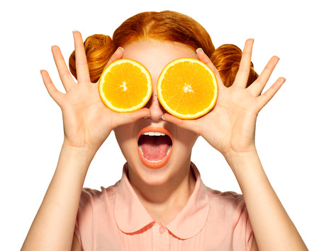 Beautiful joyful teen girl with freckles holding juicy orangesの写真素材