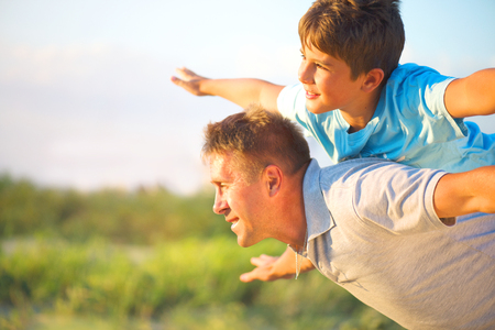 Happy father and son having fun over beautiful sky outdoorsの写真素材