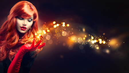Beauty glamour woman with golden magic sparks in her handの写真素材