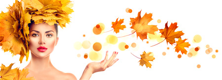 Model girl with autumn bright leaves hairstyle showing empty copy space on open hand palm for textの写真素材