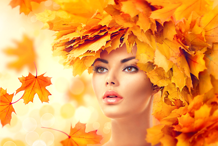 Autumn woman. Fall. Beauty model girl with autumn bright leaves hairstyleの写真素材