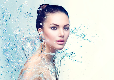 Beauty spa woman under splash of water over blue backgroundの写真素材