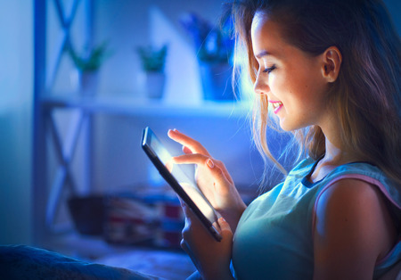 Beautiful young woman with tablet computer in a dark roomの写真素材