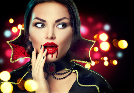 Halloween portrait. Beauty sexy vampire woman with dripping blood on her mouthの写真素材