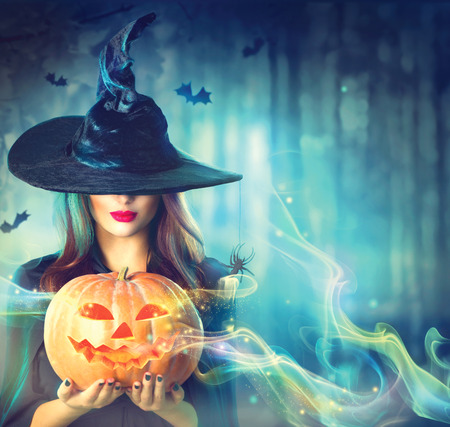Witch with a Halloween pumpkin in a dark forestの写真素材