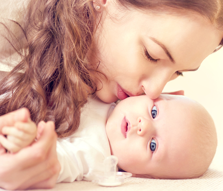 Happy mother kissing her newborn babyの写真素材