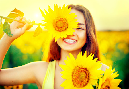 Beauty joyful teenage girl with sunflower enjoying nature