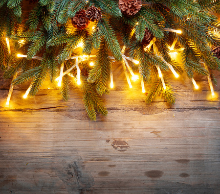 Christmas fir tree with Christmas lights over wooden backgroundの写真素材