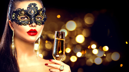 Sexy model woman with glass of champagne wearing venetian masquerade maskの写真素材