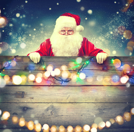 Happy Santa Claus holding wooden banner background. Christmas themeの写真素材