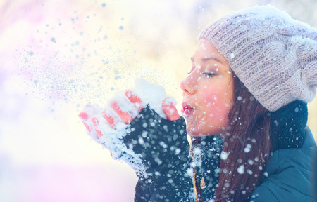 Beauty winter girl blowing snow in frosty winter parkの写真素材