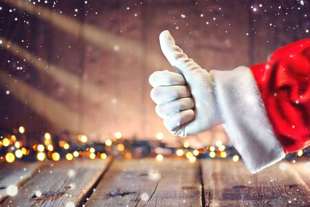 Santa Claus thumb up gesture over Christmas holiday wooden backgroundの写真素材