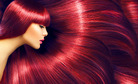 Beautiful hair. Beauty brunette woman with long straight red hair as backgroundの写真素材
