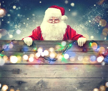 Happy Santa Claus holding wooden banner background. Christmas themeの写真素材