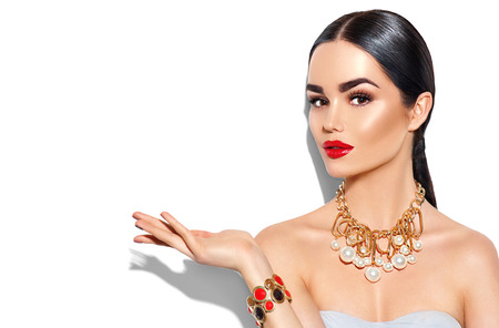 Sexy young woman with perfect makeup and trendy golden accessories showing empty copy space on the open hand palmの写真素材