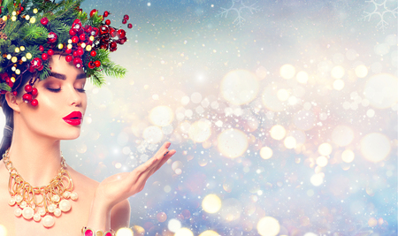 Christmas winter fashion girl blowing with magic snow in her handの写真素材