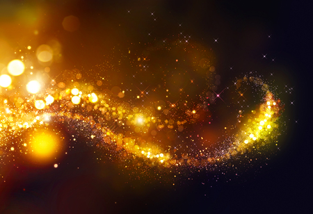 Golden Christmas glittering stars swirl over black backgroundの写真素材