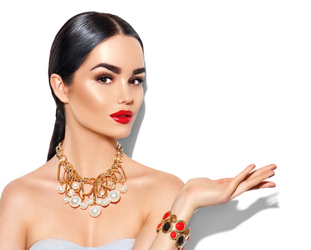Sexy young woman with perfect makeup and trendy golden accessories showing empty copy space on the open hand palmの写真素材
