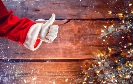 Santa Claus thumb up gesture over Christmas holiday wooden backgroundの写真素材