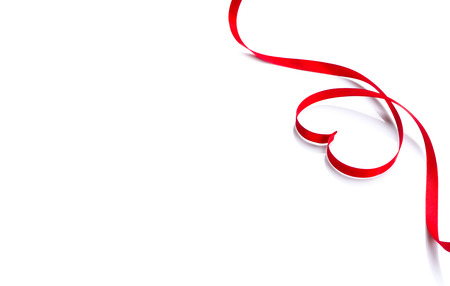 Valentine's day background. Red heart shaped satin gift ribbon isolated on whiteの写真素材
