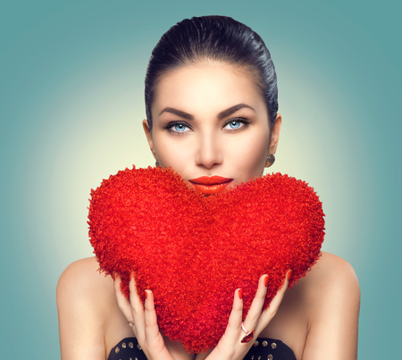 Valentine's day. Sexy model girl with heart shaped fluffy red pillowの写真素材