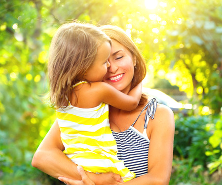 Beautiful mother and her little daughter playing in summer park togetherの写真素材