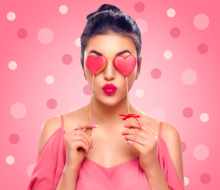 Valentines Day. Beauty joyful young fashion model girl with Valentine Heart shaped cookies in her handsの写真素材