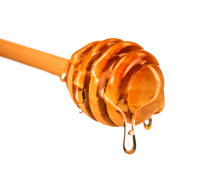 Honey dripping from honey dipper isolated on white background. Thick honey dipping from the wooden honey spoonの写真素材